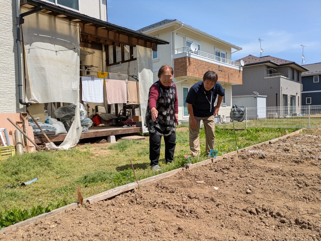 Elderly woman and caregiver talking in a vegetable garden in Sendai, Japan